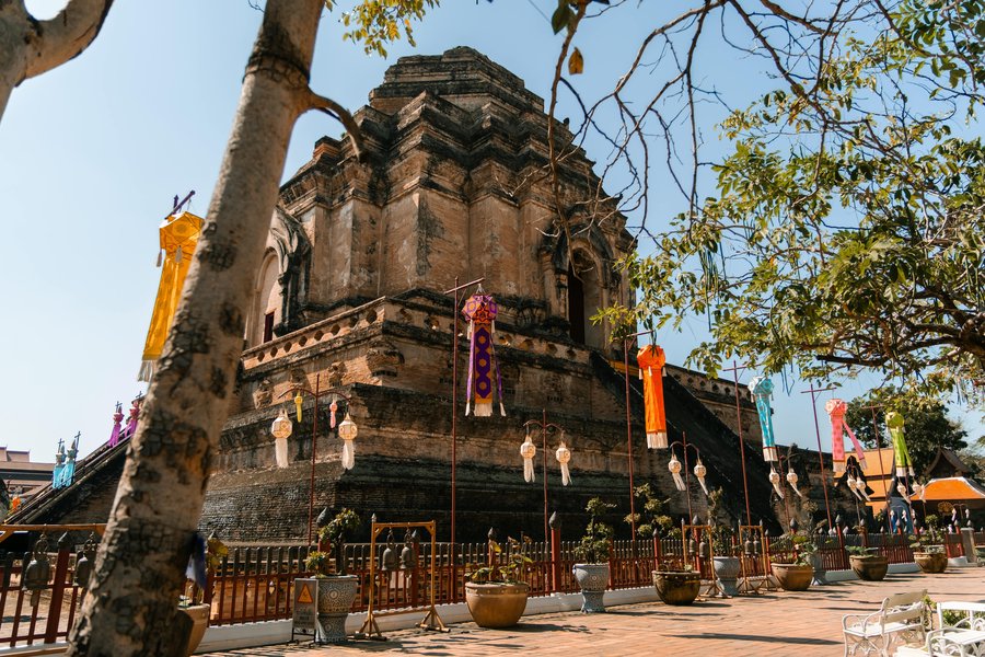 Weathered brick chedi at Wat Chedi Luang framed by trees and festival lanterns