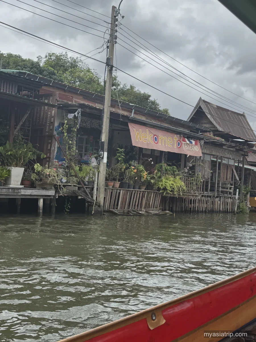 Wooden buildings beside a Bangkok canal, photographed from a boat