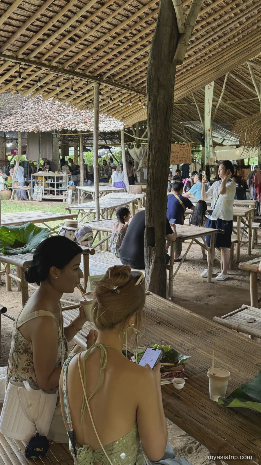 Busy open-air cafe with bamboo tables and a thatched roof in Chiang Mai