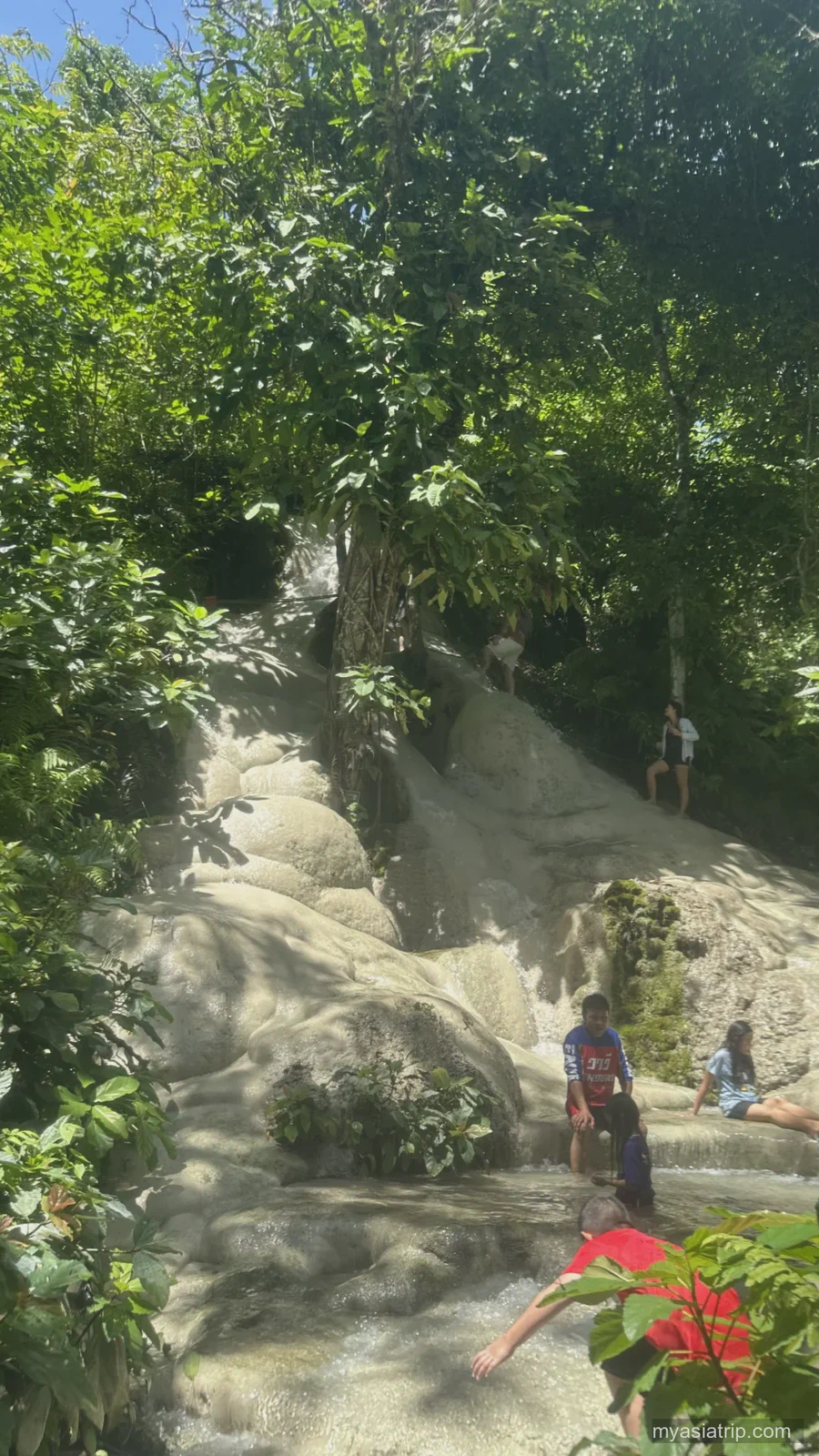 Visitors resting and climbing on pale limestone at Bua Tong Sticky Waterfall