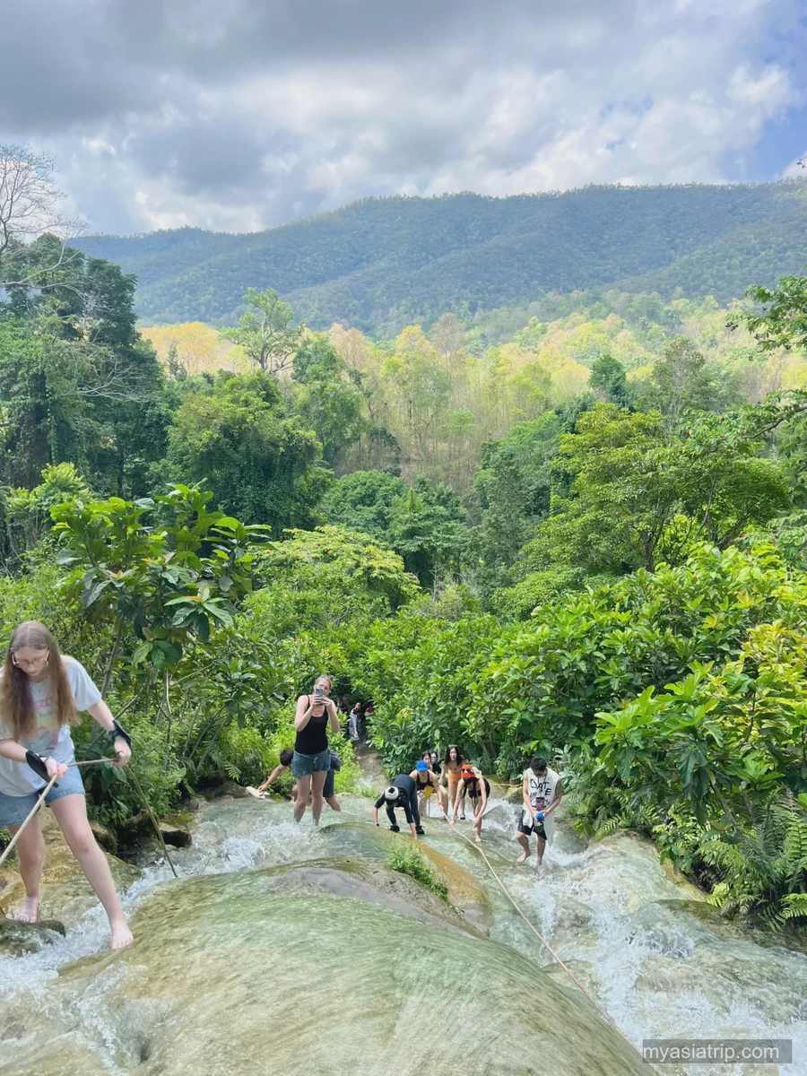 Travelers climbing the pale limestone tiers of Bua Tong Sticky Waterfall
