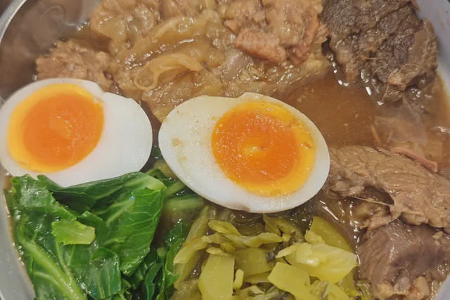 Bowl of khao soi with noodles, egg and pickled greens in Chiang Mai