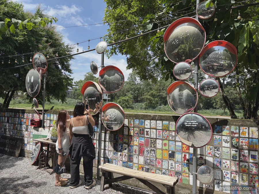 Visitors looking at mirrors and small artworks at an outdoor Chiang Mai craft space