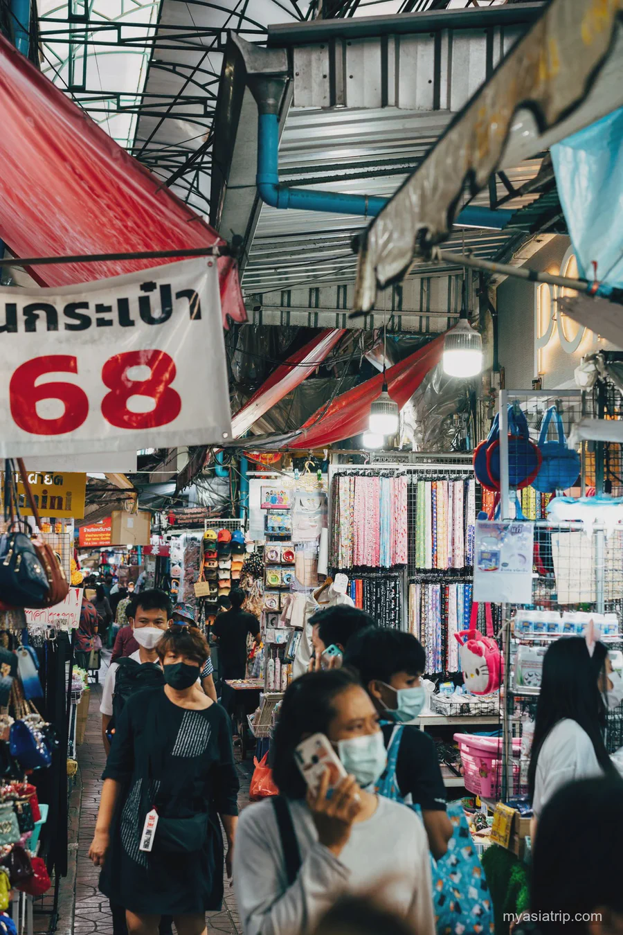 Shoppers moving through a narrow covered market aisle in Bangkok