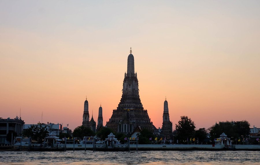 Wat Arun silhouetted across the Chao Phraya River at sunset